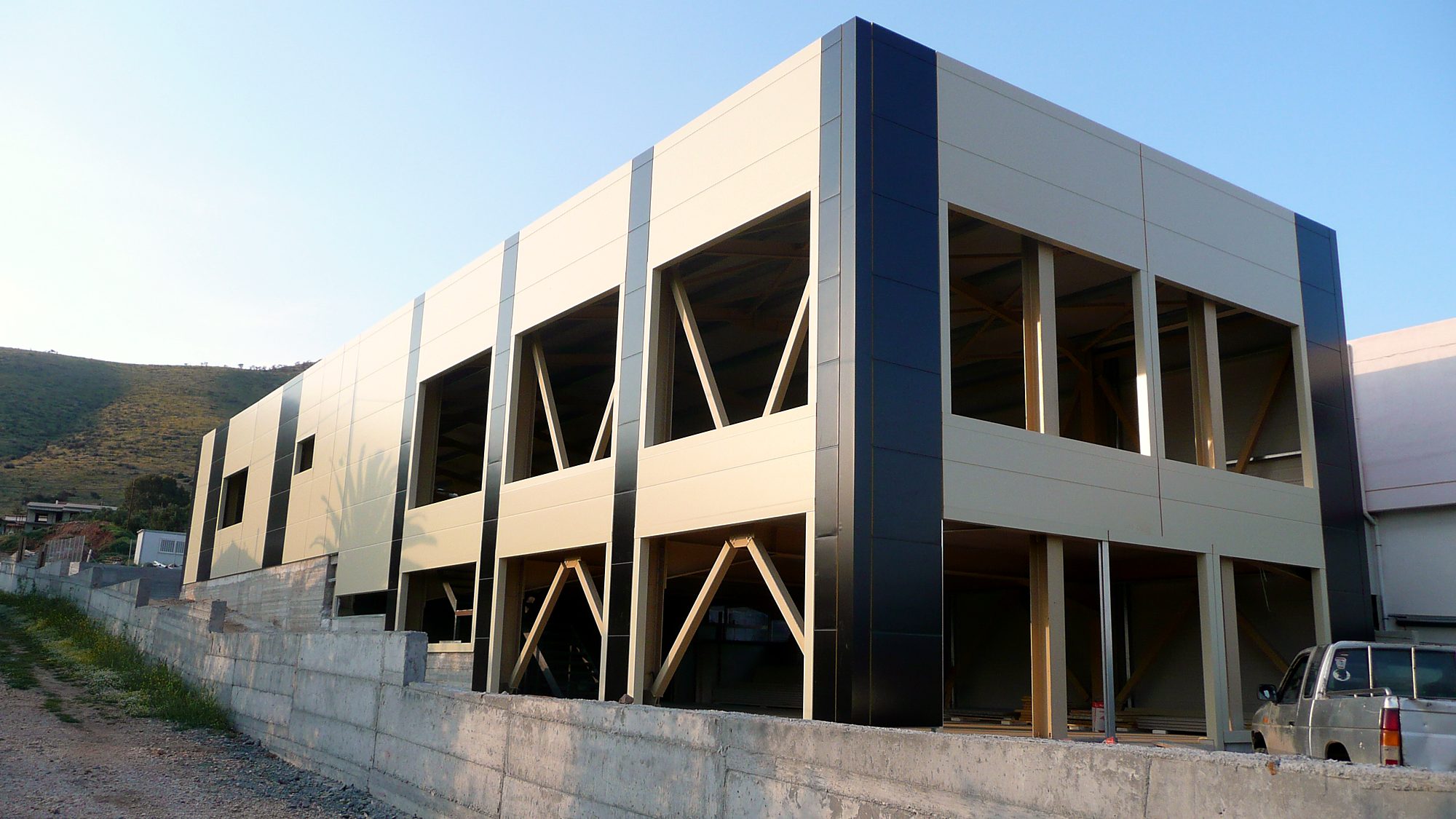 Διώροφος μεταλλικός σκελετός με διαγώνιους συνδέσμους και πάνελ πρόσοψης σε κατάστημα στον Μαραθώνα Αττικής