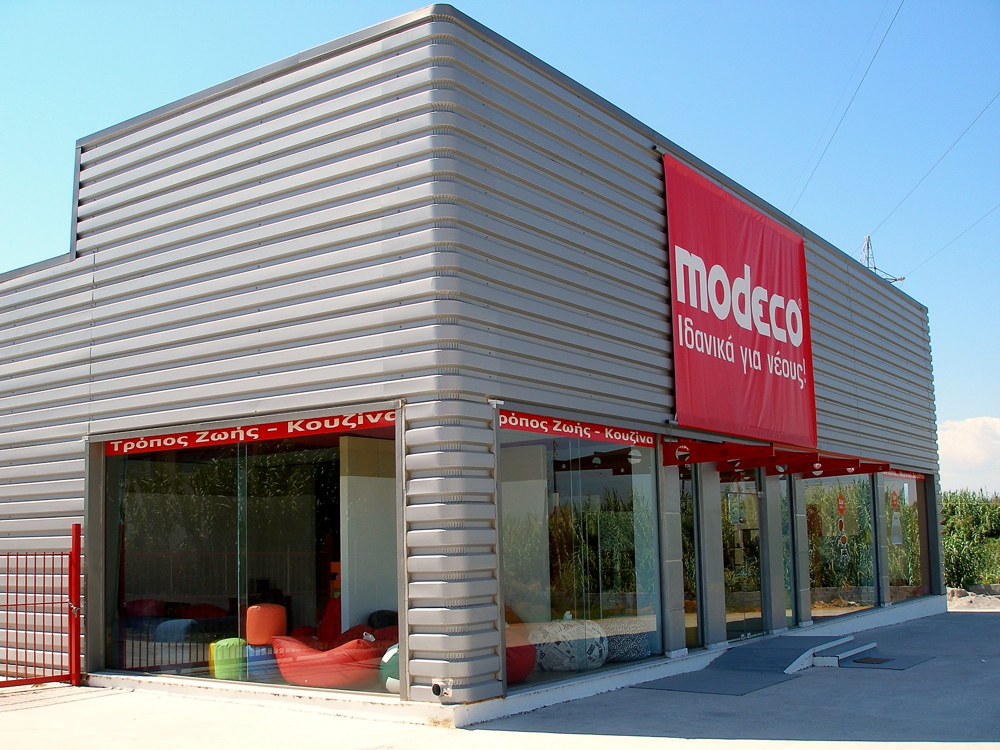 Γωνιακή όψη εκθεσιακού μεταλλικού κτιρίου Modeco με υαλοστάσια στο Ασπρόχωμα Καλαμάτας